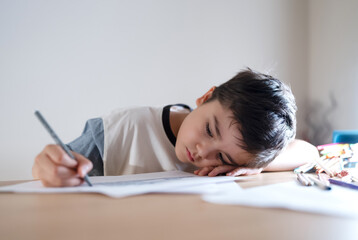 School kid writing or painting for homework, Child bored face lying head down looking out deep in thought, Boy learning online class room at home, E-learning or Homeschooling education concept