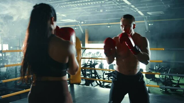 A male and female boxer train together, exchanging punches and practicing defensive techniques in a well-lit gym environment, enhancing their boxing skills. Camera 8K RAW. 