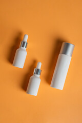 Cosmetic product in tube, bottle, lotion or serum seed on cream background. 