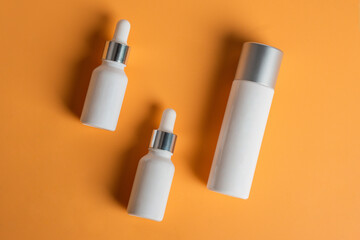 Cosmetic product in tube, bottle, lotion or serum seed on cream background. 