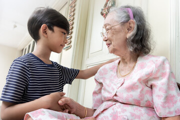 An Asian boy greeting his grandmother by shaking hands when visiting her at her home