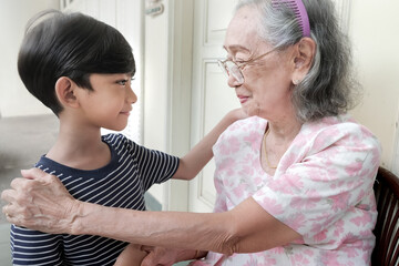 An Asian boy greeting his grandmother by shaking hands when visiting her at her home