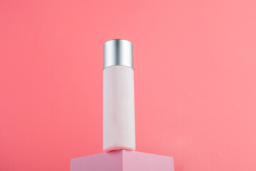 Plastic white tube for cream or lotion. Skin care or sunscreen cosmetic with stylish props on pink background.