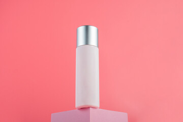 Plastic white tube for cream or lotion. Skin care or sunscreen cosmetic with stylish props on pink background.