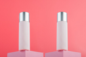 Plastic white tube for cream or lotion. Skin care or sunscreen cosmetic with stylish props on pink background.