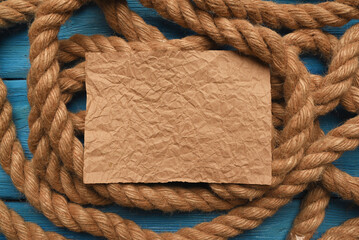 Empty blank letter page sheet and moorings rope on the blue table background. Columbus day concept.