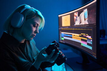a woman wearing headphones is holding a camera in front of a computer screen
