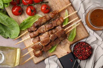 Tasty cooked marinated meat served with sauce and tomatoes on grey table, flat lay