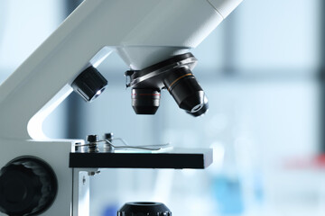 Microscope with glass slide on blurred background, closeup