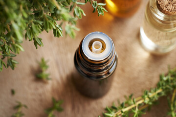 A dark bottle of aromatherapy essential oil with fresh thyme twigs