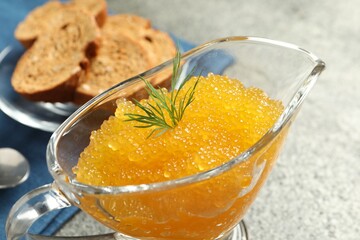 Fresh pike caviar and dill in gravy boat on grey table, closeup