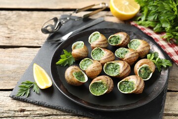 Delicious cooked snails served on wooden table