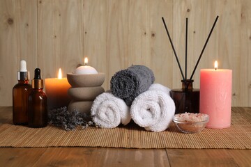 Aromatherapy. Scented candles, bottles, lavender, towels and sea salt on wooden table