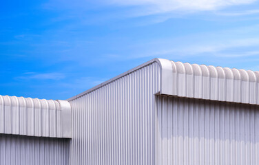 Geometric metal industrial warehouse building with 2 aluminium roof eaves against blue sky background, low angle and perspective side view with copy space 