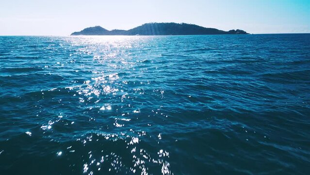 Camera flies over the water towards the island with high speed