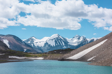 Most beautiful view to azure alpine lake against snow-covered range with few pointy peaks. Ripples...