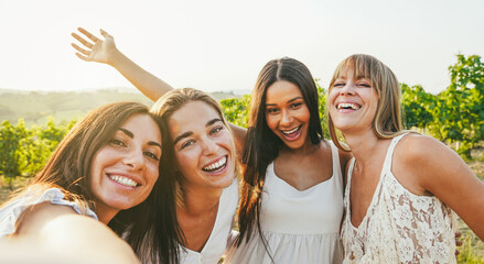 Group of female friends doing selfie during summer holidays in countryside with vineyards in background - Summer vacation, party and travel concept - Focus on blond girls faces