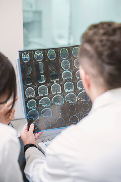 two doctors examine an MRI image of the brain in an MRI room. Blurred image
