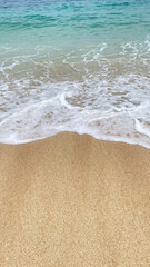 a close up of a wave crashing onto a sandy beach.