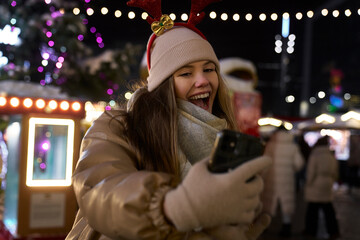 Young woman taking selfie on Christmas Market at night