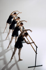 Symmetry and grace in ballet. Four flexible girls, ballet dancers standing at barre and training...