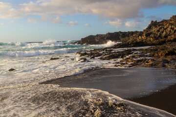Obraz premium Black volcanic rocks on the Atlantic coast at sunset. Playa de las Malvas, Lanzarote, Canary Islands, Spain