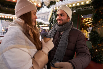 Caucasian couple drinking mulled wine and chatting on Christmas market