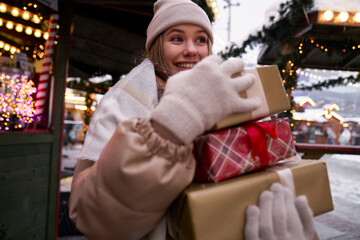 Young caucasian woman carrying a pile of Christmas presents