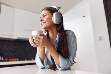 Woman enjoying music with headphones and coffee at table in cozy atmosphere