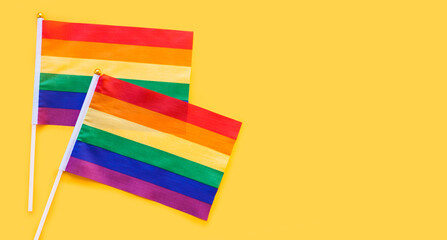 LGBT rainbow flag flat lay on yellow color background. gay marriage, human rights, june parade, lgbtq proud history month concept, coming out day. top view, place for text or logo