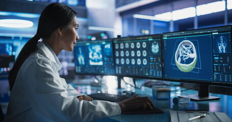 Female Asian Neurologist Using Desktop Computer With Human Brain MRI Scans In Modern Medical...