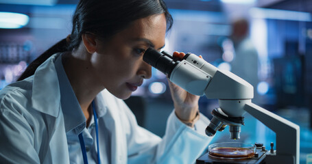 Medical Development Laboratory: Portrait of Asian Female Scientist Using Microscope, Analyzes Petri...