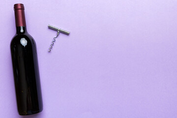 One Bottle of red wine with corkscrew on colored table. Flat lay, top view wth copy space
