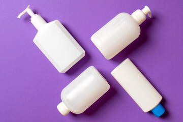Set of White Cosmetic containers isolated on colored background, top view with copy space. Group of plastic bodycare bottle containers with empty space for you design