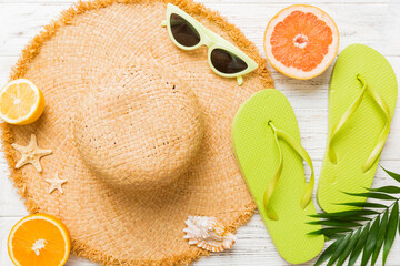 Top view of various seashells placed near colorful fruit and stylish summer accessories on table...