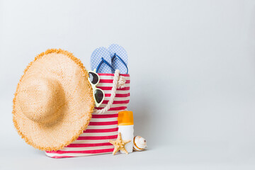 Stylish bag with beach accessories . Summer holiday concept. Top view of beach bag with sunscreen...