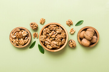 Walnut kernel halves, in a wooden bowl. Close-up, from above on colored background. Healthy eating...