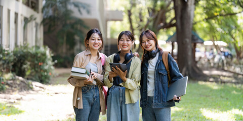 female student is walking to class with friends and stop to look at the camera. back to school concept - obrazy, fototapety, plakaty