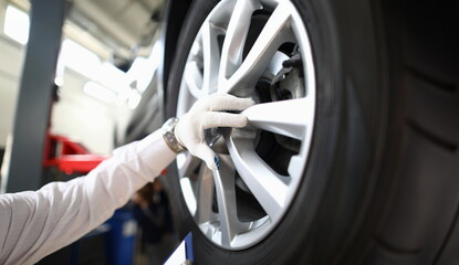 Focus on specialist male hand wearing white glove and inspecting titan discs of modern sporting automobile wheels. Machinery repairman and service station concept