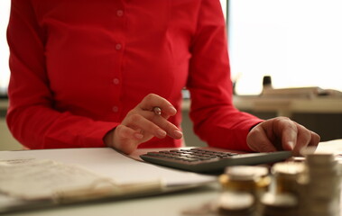 Focus on woman hand holding pen and taping calculator. Accountant sitting at table with papers and...