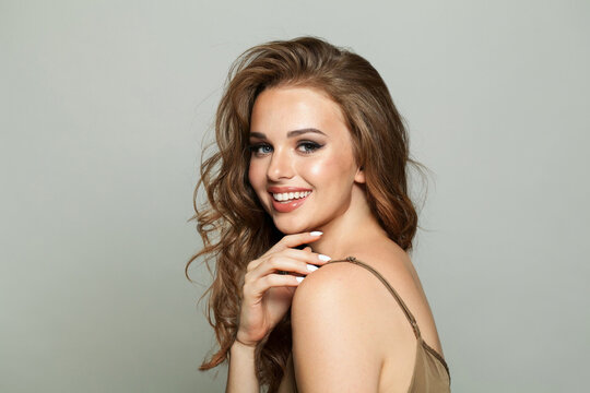 Happy young woman brunette with long healthy hair and fresh silky skin posing on white background. Fashion beauty studio portrait