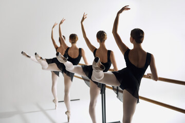 Teen girls, ballet dancers practicing at barre, focusing attention on technique and elegance against grey studio background. Concept of ballet, art, dance studio, classical style, youth