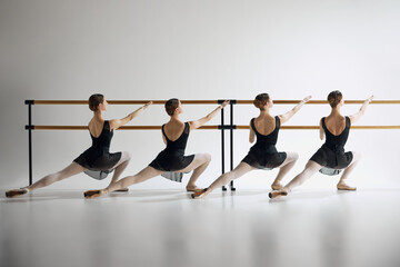 Ballet practice at barre. Teen girls, ballet dancers in black costumes training, preparing for...