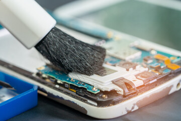 Asian technician repair and cleaning dirty micro circuit main board of smartphone electronic...
