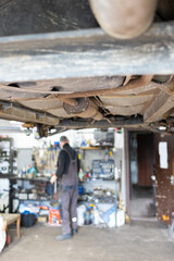 Auto mechanic repairing a car in auto repair shop, blurred background.