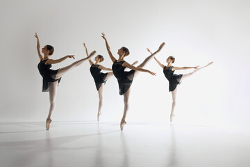 Inspiration. Young teen girls, graceful ballerinas in back costumes standing on pointe, training, performing complex ballet moves. Concept of ballet art, dance studio, classical style, youth