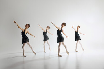 Beauty of ballet dance. Elegant teen girls, ballerinas in black leotards training, practicing against grey studio background. Concept of ballet art, dance studio, classical style, youth