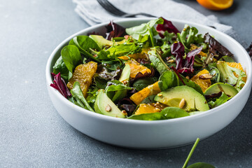 Fresh salad Organic avocado and spinach leaves  with orange and olive oil in a white plate. vegetarian dish