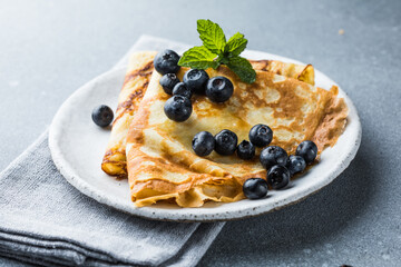 Stack of traditional russian pancakes blini on gray background with copy space. Homemade russian thin pancakes blini.