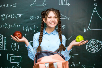 Schoolgirl girl enjoys lunch of two ripe apples.